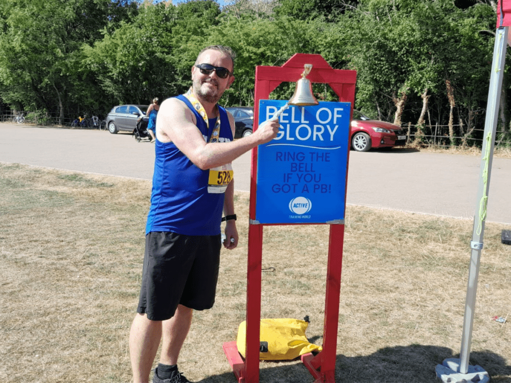 David Buckley ringing a bell labeled 'The Bell of Glory' for getting a personal best.