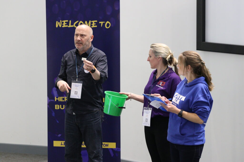 CEO of Home-Start Herts, Suzy Moody, and Youth Talk's Fundraising Manager, Rachel, announcing the winners of the charity raffle auction at the Hertfordshire Business Growth Show 2023.